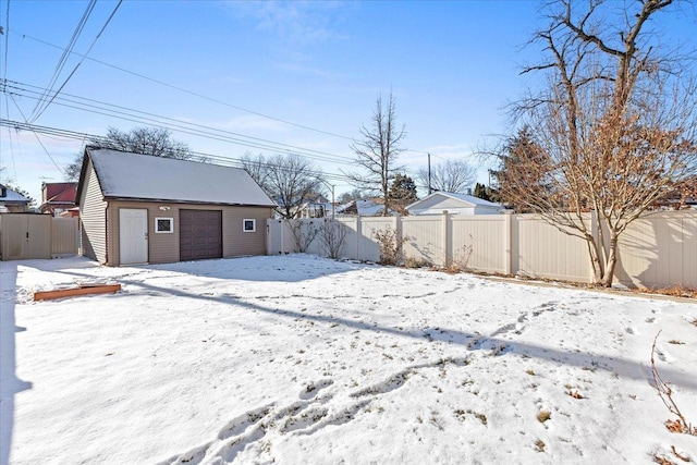 snowy yard featuring a garage and an outdoor structure