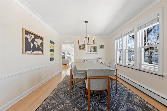 dining space featuring a baseboard heating unit, an inviting chandelier, crown molding, and wood-type flooring