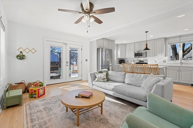 living room featuring light wood-type flooring, french doors, and ceiling fan