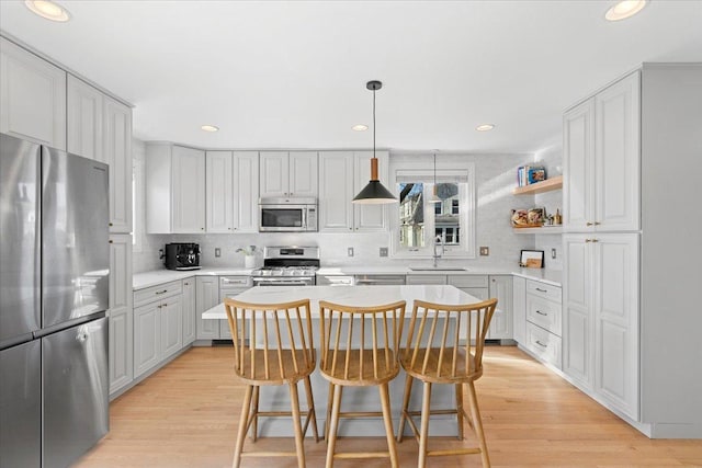 kitchen featuring tasteful backsplash, a kitchen island, sink, light wood-type flooring, and stainless steel appliances