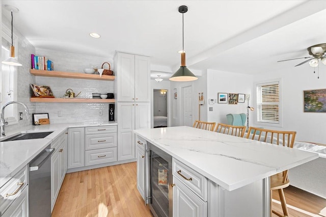 kitchen with a kitchen bar, decorative light fixtures, beverage cooler, stainless steel dishwasher, and sink