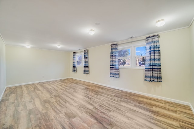 empty room with crown molding and light hardwood / wood-style flooring