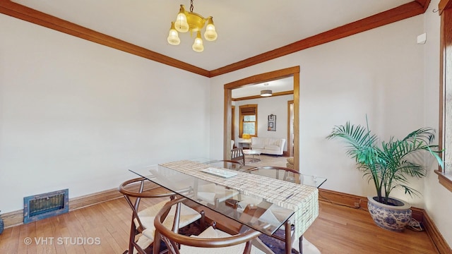 dining room with crown molding, wood-type flooring, and a chandelier