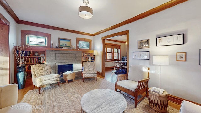 living area featuring ornamental molding, a fireplace, and light hardwood / wood-style floors