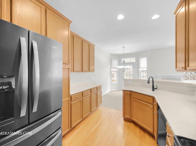 kitchen with sink, stainless steel fridge, hanging light fixtures, range, and light wood-type flooring