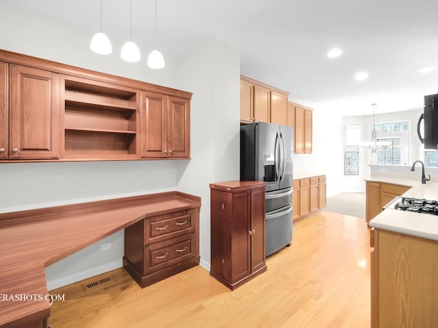 kitchen with a chandelier, built in desk, stainless steel fridge with ice dispenser, hanging light fixtures, and light hardwood / wood-style flooring