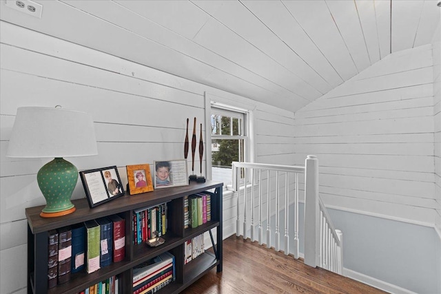 corridor featuring vaulted ceiling, wooden ceiling, wood-type flooring, and wooden walls