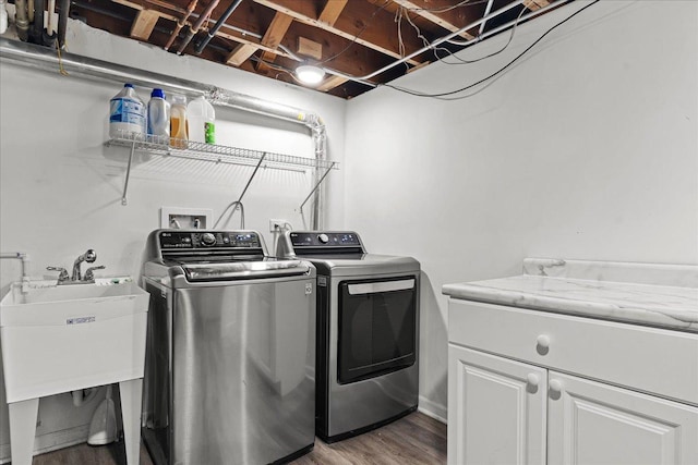 laundry room featuring hardwood / wood-style floors, washing machine and dryer, sink, and cabinets