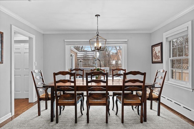 dining space with a baseboard heating unit, ornamental molding, a chandelier, and wood-type flooring