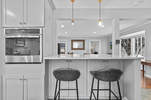 kitchen with a breakfast bar area, light stone countertops, and ornamental molding