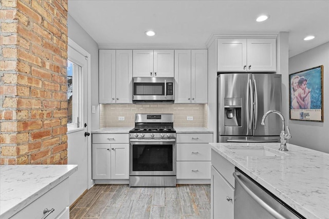 kitchen with decorative backsplash, light stone counters, white cabinets, and stainless steel appliances