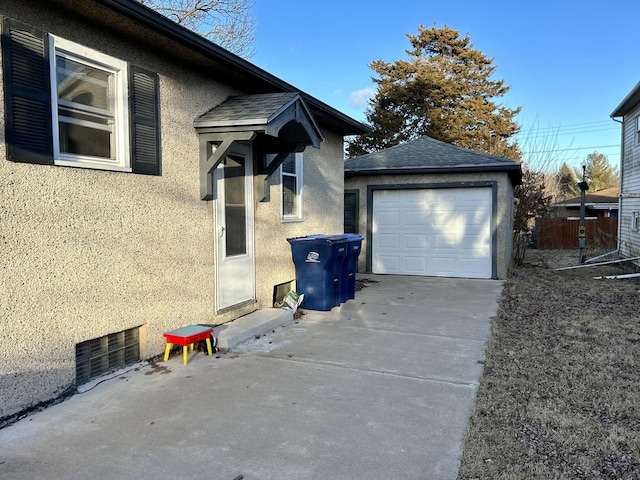 view of side of property featuring a garage, a shingled roof, an outdoor structure, and stucco siding