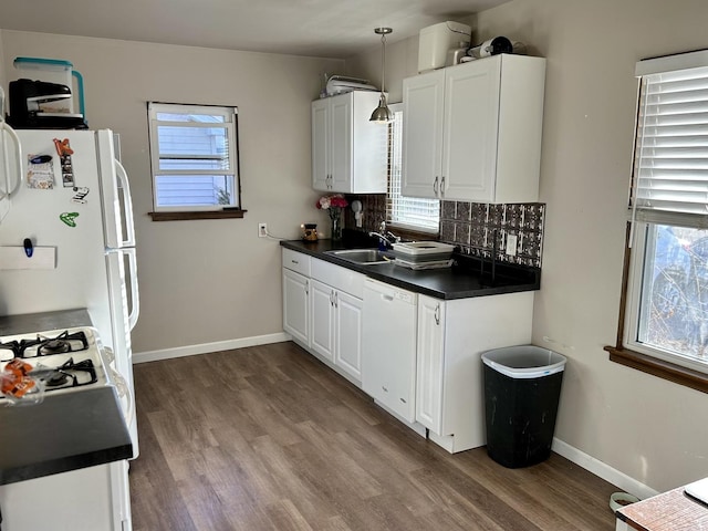 kitchen featuring tasteful backsplash, dark countertops, white appliances, and a sink