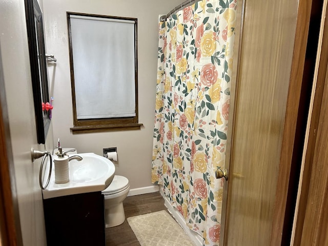 bathroom featuring toilet, a shower with shower curtain, wood finished floors, vanity, and baseboards