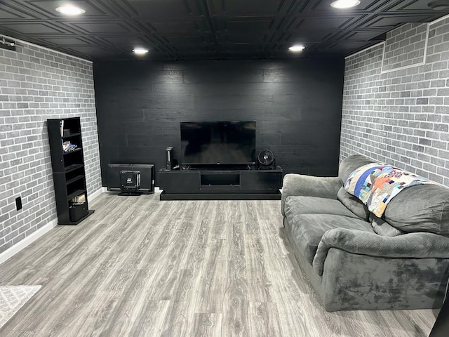 living area with an ornate ceiling, brick wall, and wood finished floors