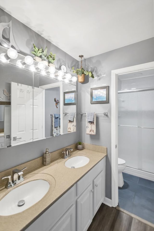 bathroom with vanity, toilet, an enclosed shower, and wood-type flooring