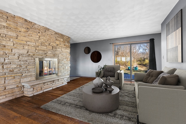 living room with dark wood-type flooring and a stone fireplace