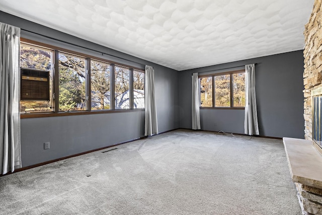 carpeted empty room featuring a fireplace and plenty of natural light