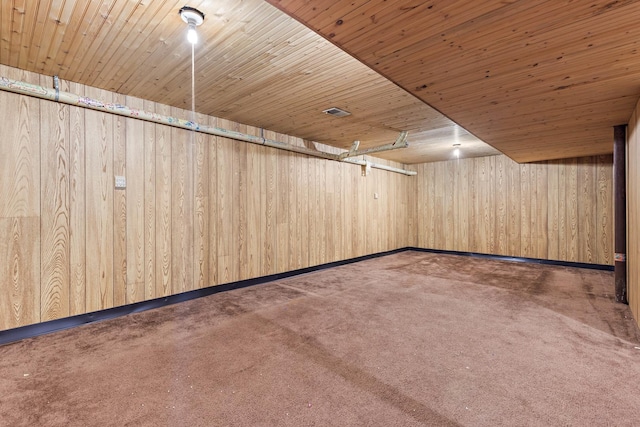 interior space with wooden ceiling, dark carpet, and wood walls