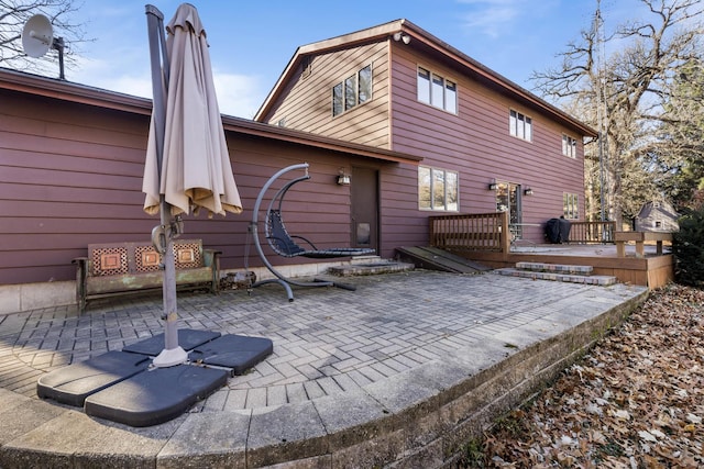 back of house with a deck and a patio