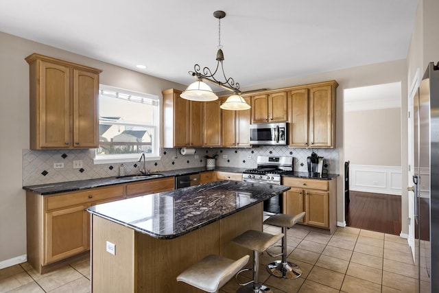 kitchen featuring sink, a kitchen island, decorative light fixtures, stainless steel appliances, and light tile patterned flooring