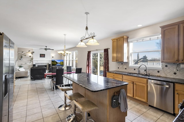 kitchen with appliances with stainless steel finishes, hanging light fixtures, light tile patterned floors, decorative backsplash, and sink