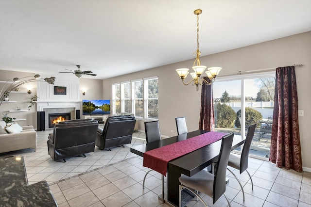 tiled dining area featuring ceiling fan with notable chandelier and a large fireplace