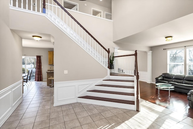 stairs featuring decorative columns and tile patterned floors