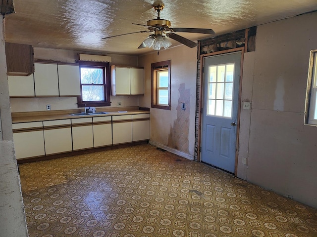 kitchen featuring ceiling fan, white cabinets, and sink