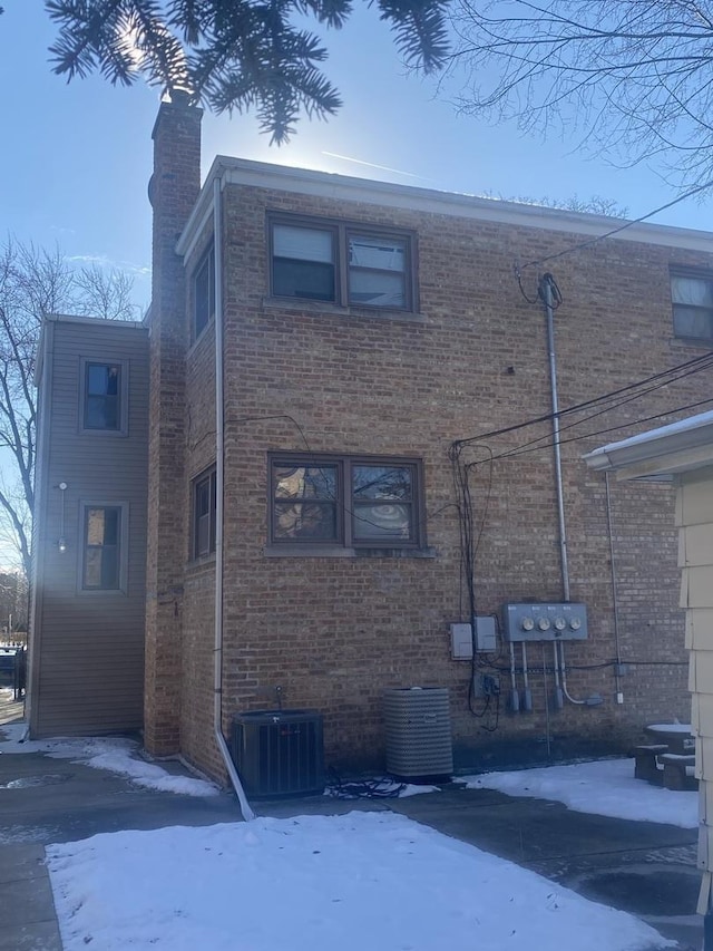 snow covered property with central AC