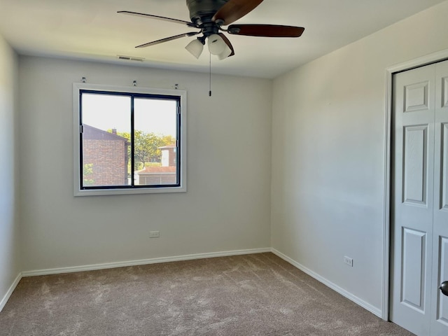 spare room with ceiling fan and light colored carpet