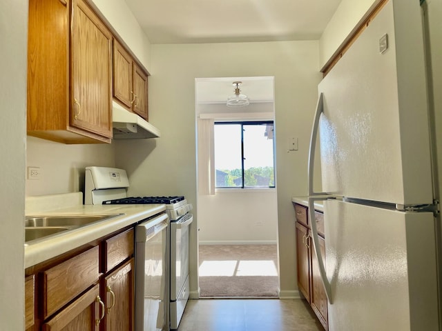 kitchen featuring light colored carpet, sink, and white appliances