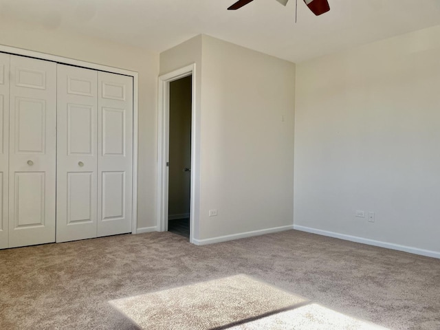 unfurnished bedroom featuring ceiling fan, light colored carpet, and a closet