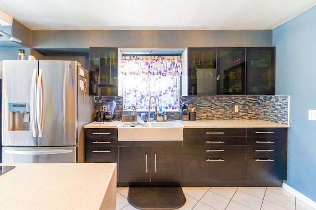 kitchen with backsplash, stainless steel refrigerator with ice dispenser, sink, light tile patterned floors, and dark brown cabinets