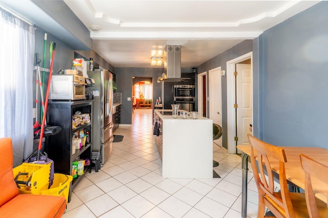 kitchen featuring white cabinets, light tile patterned floors, island range hood, and stainless steel appliances