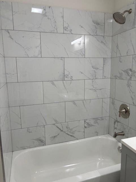 bathroom with tiled shower / bath combo and vanity