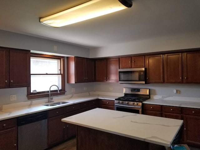 kitchen featuring appliances with stainless steel finishes, a center island, light stone counters, and sink