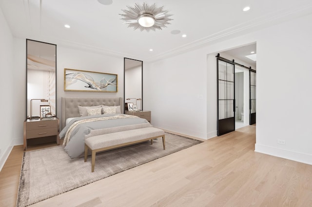 bedroom with light hardwood / wood-style floors, ornamental molding, and a barn door