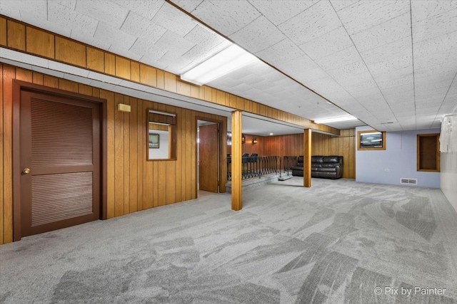 basement featuring carpet and wood walls