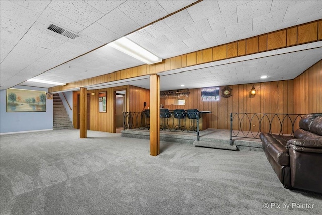 basement with bar, carpet floors, and wood walls