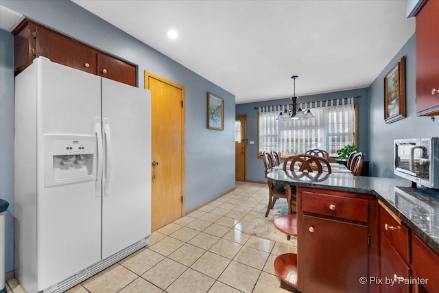 kitchen featuring hanging light fixtures, white fridge with ice dispenser, and light tile patterned floors