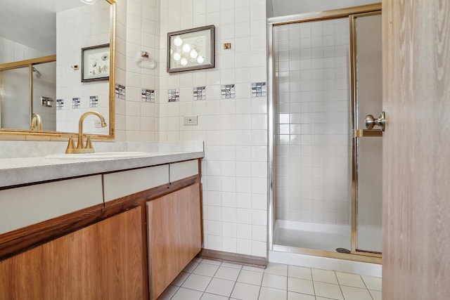 bathroom with tile patterned flooring, vanity, a shower with door, and tile walls