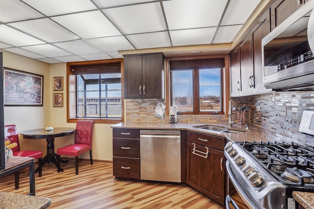 kitchen with light stone countertops, appliances with stainless steel finishes, sink, and dark brown cabinets