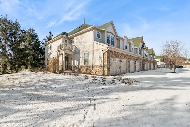 view of snowy exterior with a balcony and a garage