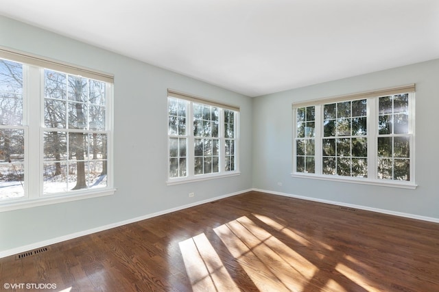 unfurnished room featuring plenty of natural light and dark hardwood / wood-style flooring