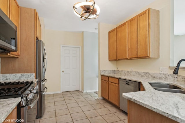 kitchen featuring appliances with stainless steel finishes, light stone countertops, sink, and light tile patterned floors