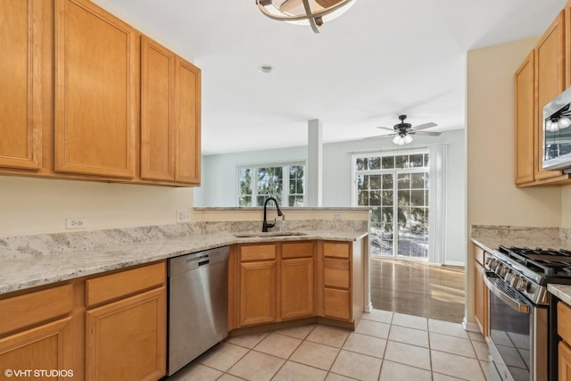 kitchen with sink, light tile patterned floors, appliances with stainless steel finishes, kitchen peninsula, and light stone countertops