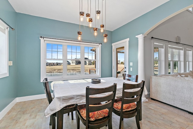 dining room with decorative columns, a healthy amount of sunlight, and light wood-type flooring