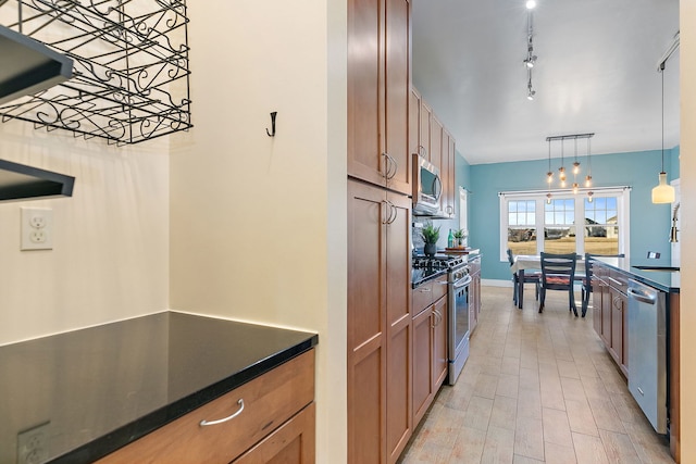 kitchen with light hardwood / wood-style flooring, hanging light fixtures, track lighting, and appliances with stainless steel finishes