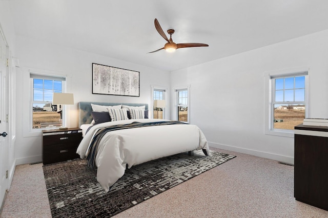 carpeted bedroom with ceiling fan and multiple windows